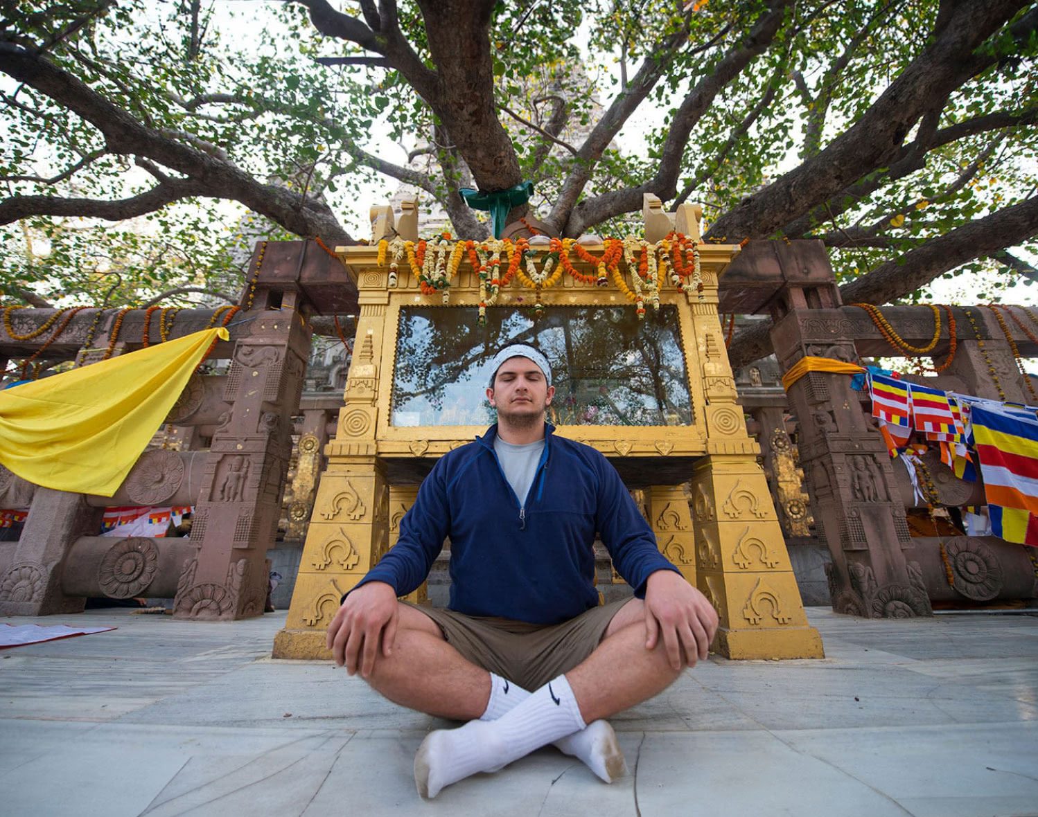 A young man crosses his legs and meditates in a sitting position.