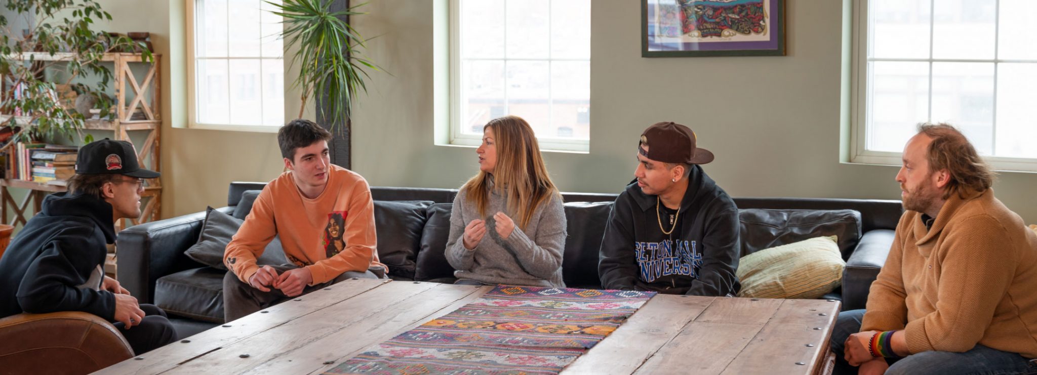 A group of young men sit down at a table during a therapy session.