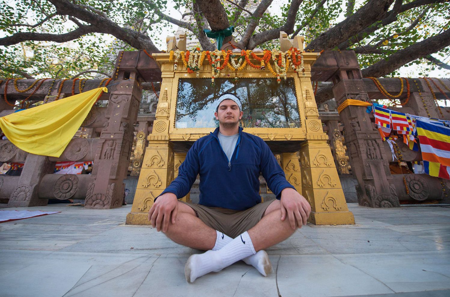 A young man crosses his legs and meditates in a sitting position.