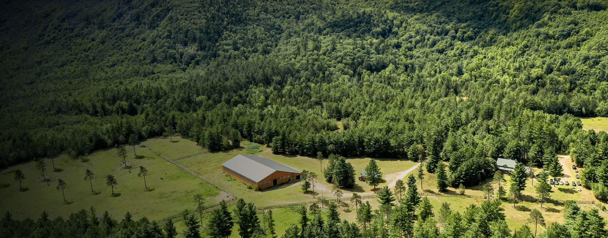 An aerial view of the Foundation House ranch surrounded by deep forest.