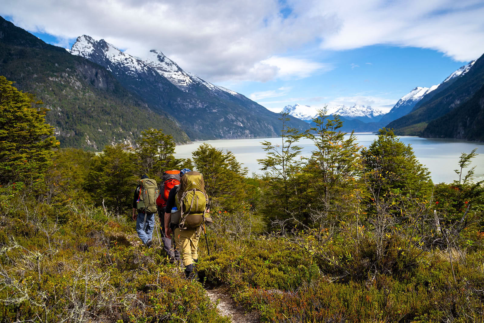 Young men hike along a river in a vast wilderness of Patagonia, Chile.