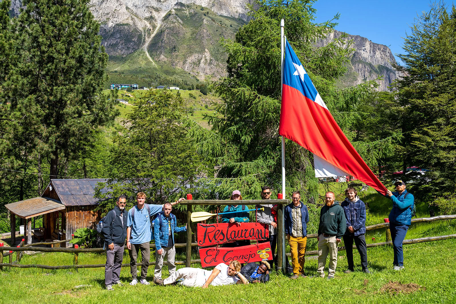 A group of men stand under the Chilean flag outside in Patagonia.