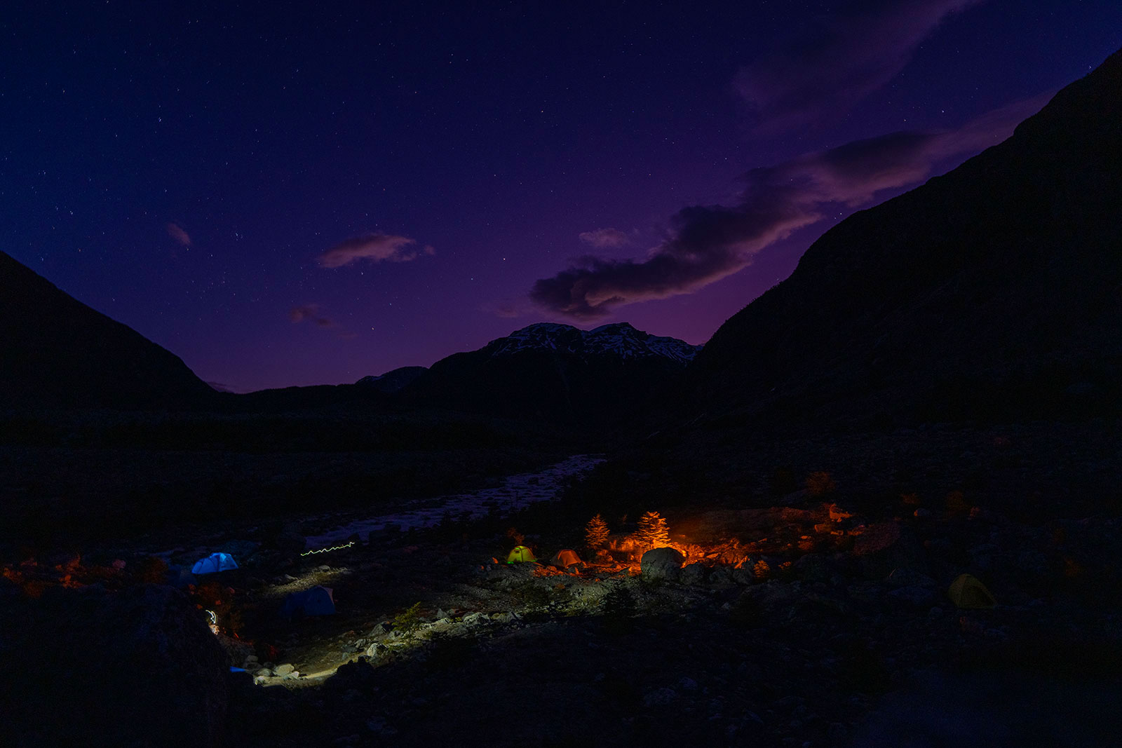 A mountain range in dark colors with illuminated city below it in Patagonia.