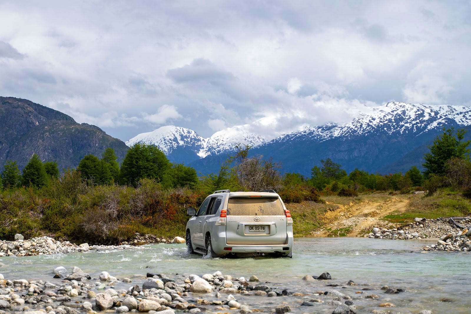 A dirty van drives through a river in Patagonia, Chile