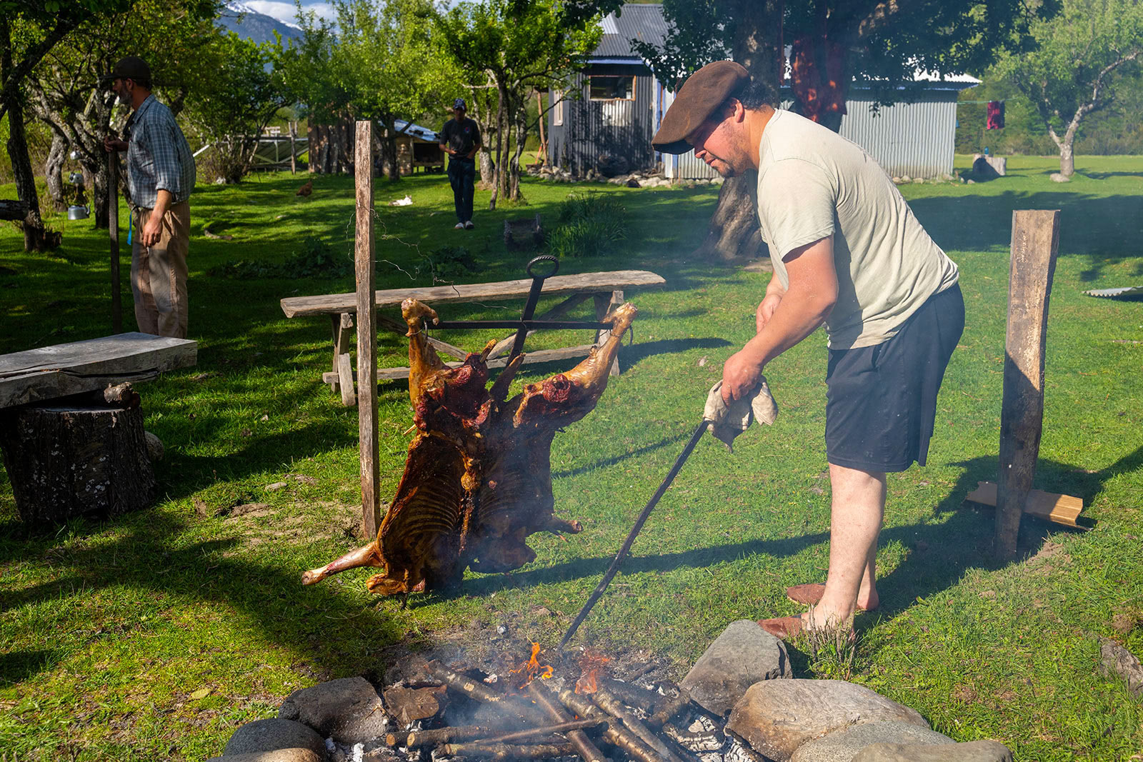 A man stands over an open fire cooking meat in Patagonia, Chile.